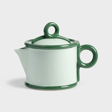 Green ceramic teapot on a light gray background.