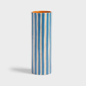 Tall cylindrical vase with blue and orange vertical stripes on a light gray background.