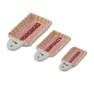 Three ceramic spoons shaped like rectangle cakes decorated with jam and coconut.
