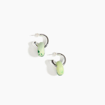 A pair of open hoop earrings in silver with a resin piece hanging off the hoop in green.