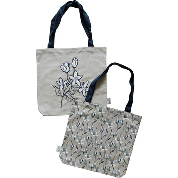 Front and back view of a tote bag embroidered with magnolia flowers on the front and printed with magnolias on the back.