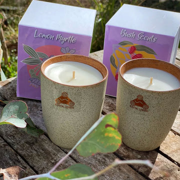 A stone mug tumbler in speckled brown with an orange sticker and a candle inside.