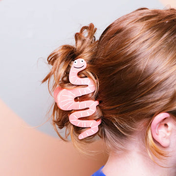 Pink worm-shaped hair clip with a face on a white background.