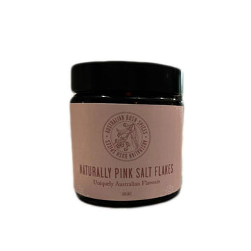 A black jar with a dark musk pink product label with the text 'Naturally Pink Salt Flakes'.