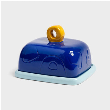 Blue butter dish with a yellow handle on a light grey background.