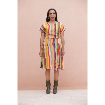 Woman wearing a colorful matching striped skirt and top against a pink background.