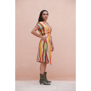 Woman wearing a colorful matching striped skirt and top against a pink background.