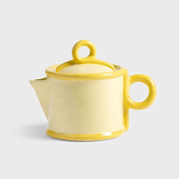 Yellow ceramic teapot on a light grey background.