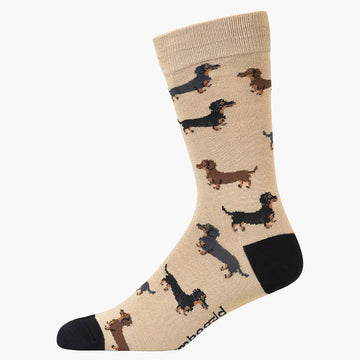 A light brown sock with a black heel and toe and illustrated with dachshunds. 