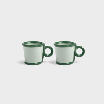 Two green ceramic mugs on a white background.