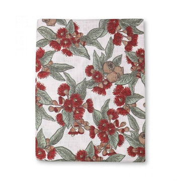 Floral patterned table cloth folded up with red flowers and green leaves on a white background.