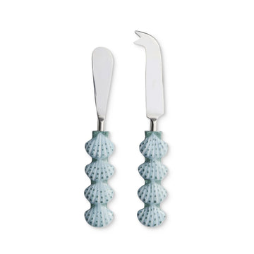 Two cheese knives with shell-shaped handles on a white background.