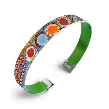 A cuff bangle printed with artwork by Murdie Morris on the outside and green on the inside.