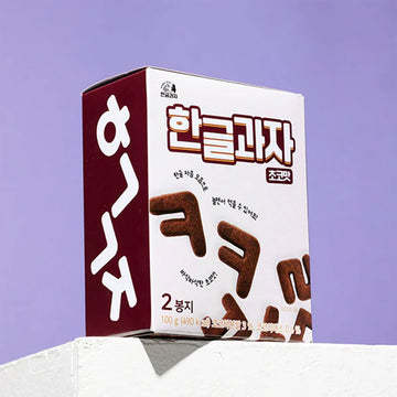 Box of Korean alphabet chocolate cookies on a purple background.