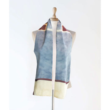 A silk scarf is draped over the shoulders of a mannequin and printed with abstract artwork in blue, red and cream.