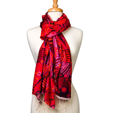 A silk scarf tied around the neck of a mannequin. The scarf has red and purple shades in a design by Helen Robertson.
