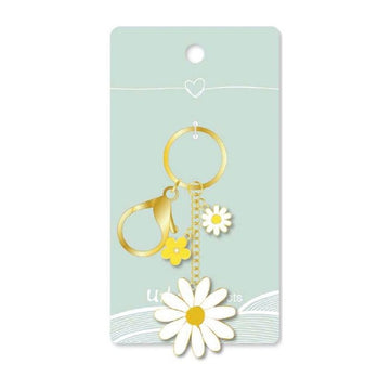Gold and white daisy keychain on a light blue card with a heart symbol.