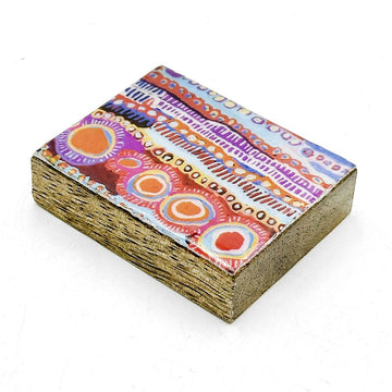A wooden block magnet printed with artwork by Murdie Morris on top.