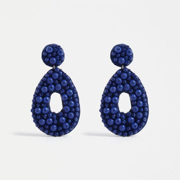 A pair of drop earrings with a circle top and tear drop bottom covered with blue beads.