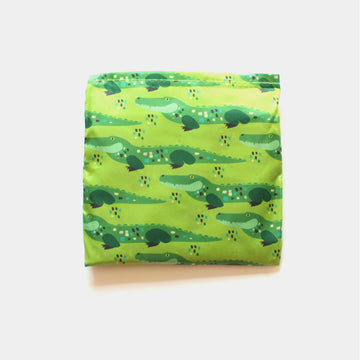 A reusable shopping bag in light green illustrated with a repeat pattern of crocodiles.
