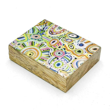 A wooden block magnet printed with artwork by Cedric Varcoe on top.