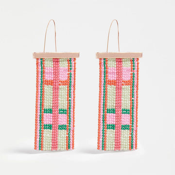 A pair of drop earrings with a rose gold bar and beads hanging off the bar making a check pattern.