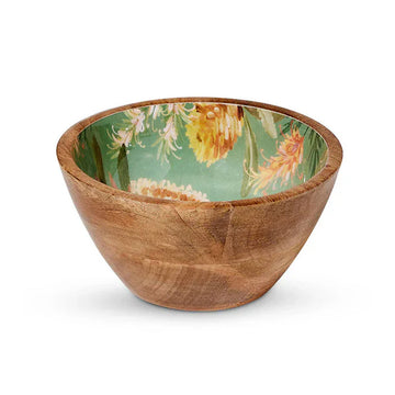A small wooden bowl with flowers printed on the inside on a green background.