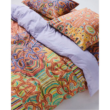 A square European cushion printed with Indigenous artwork in orange.