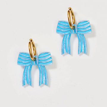 A pair of gold hoop earrings with blue bows attached to the hoop.