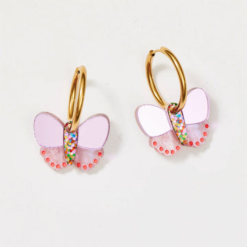 A pair of gold hoop earrings with light pink butterflies attached to the hoops.