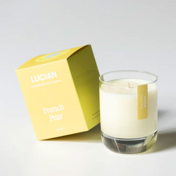 A glass candle next to a yellow box with the text 'Lucian French Pear'.