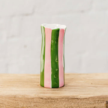 A small ceramic hand painted vase with pink and green vertical stripes.