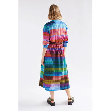 Woman wearing a colorful striped dress on a white background.