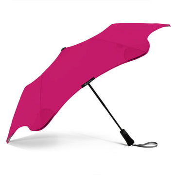 A pink umbrella is open and resting on its black handle.