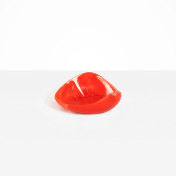 A small resin bowl shaped like a leaf in red.