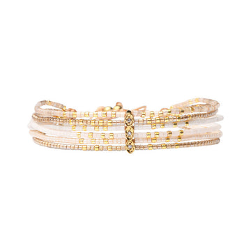 Stack of gold and white beaded bracelets on a white background.