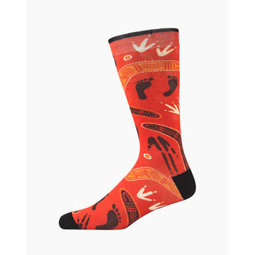 A red sock with a black heel and toe and printed with Aboriginal artwork of footprints of humans and animals and boomerangs.