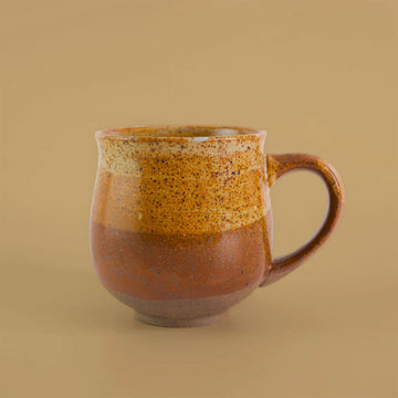 Ceramic mug with brown and orange speckled design on a beige background.