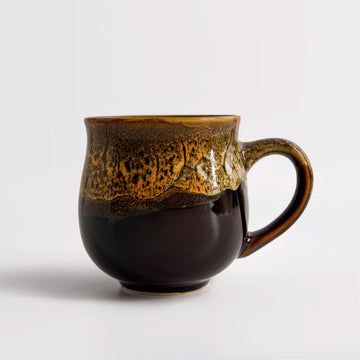 Brown ceramic mug with speckled design on a white background.