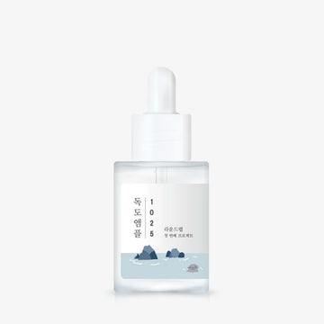 Skincare serum bottle with a white cap on a light gray background.