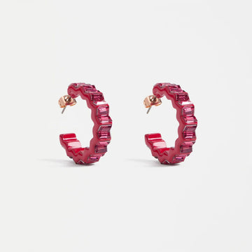 Pink hoop earrings with a zig zap shape on a light gray background.