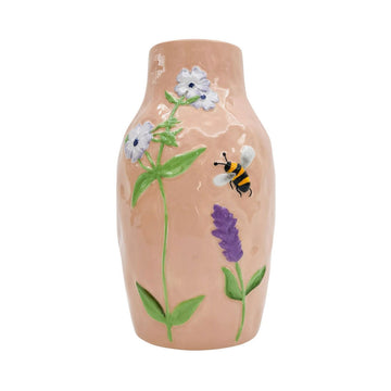 A ceramic light pink vase embossed with flowers and a bee.