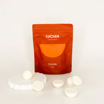 An orange packet with the text 'Lucian Fireside' and wax melts in front.