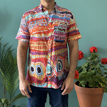 Front view of a model wearing a colourful shirt with artwork by Murdie Morris with jeans.