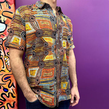 Front view of a model wearing a shirt printed with artwork in browns and yellows.