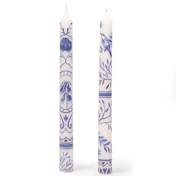 Two white candles with blue floral patterns on a white background.