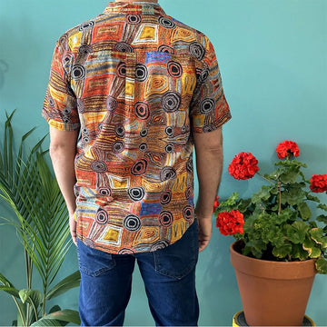 Front view of a model wearing a shirt printed with artwork in browns and yellows.