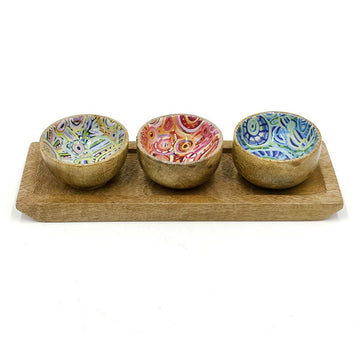 A set of three wooden bowls on a wooden tray. The inside of the bowls are printed with artwork by Cedric Varcoe.