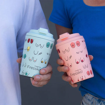 A ceramic reusable coffee mug in pink illustrated with different breasts.
