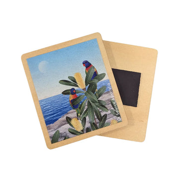 A wooden magnet illustrated with two rainbow lorikeets in a banksia plant overlooking the ocean.